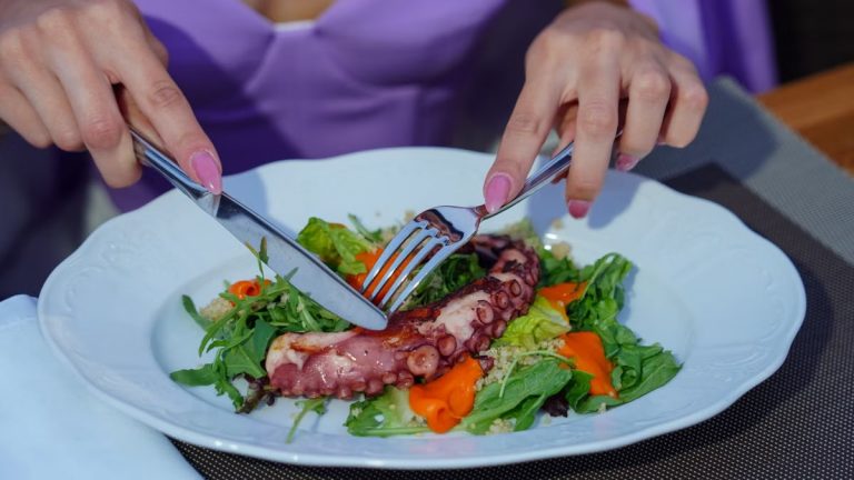 Woman enjoying an octopus salad with fresh greens outdoors. Vibrant and appetizing.