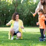 A family enjoys a playful day with bubbles in a sunny park setting.