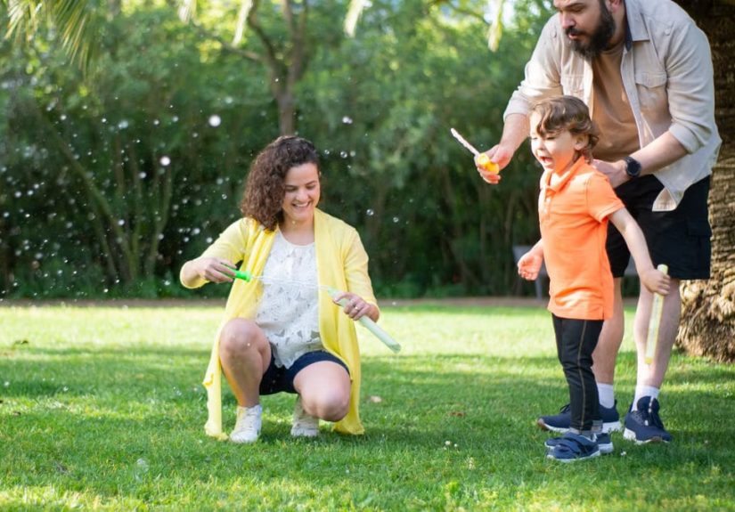 A family enjoys a playful day with bubbles in a sunny park setting.